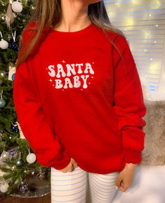 Get festive with our Santa Baby Crewneck Sweatshirt! The Unisex Sizing makes the sweatshirt run slightly larger than your average sweatshirt for women. Most men find their normal size to be more snug. If you want a slightly looser fit, size up one size. Please check out our size chart for measurements to ensure an accurate fit. PLEASE BE SURE TO INPUT YOUR CORRECT SIZE/COLOR + SHIPPING ADDRESS. We will not be responsible if it is incorrect! Refunds/Exchanges accepted, please read our Refund Poli Cute Red Winter Sweatshirt, Cute Red Sweatshirt For Winter, Cute Red Crew Neck Sweater, Cute Red Long Sleeve Sweatshirt, Christmas Long Sleeve Sweatshirt For Streetwear, Cute Fleece Crew Neck Sweater, Casual Crew Neck Hoodie For Holiday, Casual Holiday Hoodie With Crew Neck, Casual Christmas Hoodie With Crew Neck