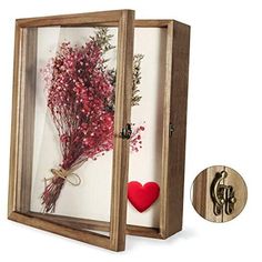 a wooden frame with dried flowers in it and a red heart hanging from the front