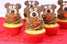 some cupcakes with chocolate frosting and teddy bears on top are sitting on a red tablecloth