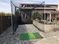 a backyard area with a golf mat and net