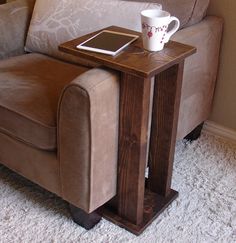 a table with two remotes and a tablet on it next to a couch in a living room