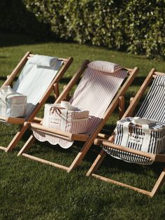 two lawn chairs sitting in the grass next to each other on top of a lush green field