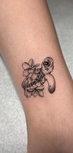 a tattoo on the leg of a woman with flowers and a turtle in it's shell