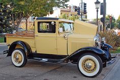 an old yellow truck is parked on the street