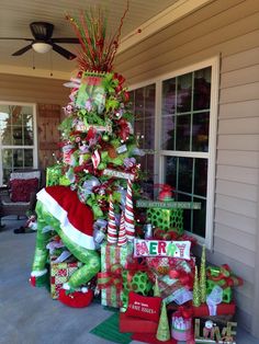 a christmas tree is decorated with presents and candy canes for the holiday season in front of a house