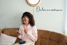 a woman sitting on a couch looking at her cell phone while holding a blue bowl