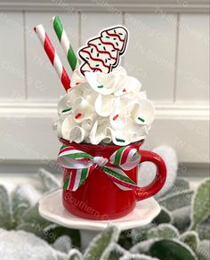 a red cup filled with whipped cream and candy canes on top of a saucer