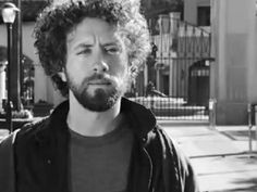 a black and white photo of a man with curly hair looking off to the side