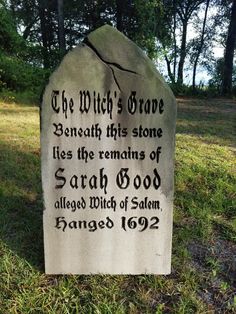 a grave marker in the grass with writing on it and trees in the background,