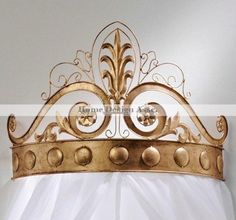 a gold metal crown on top of a white bed sheet in front of a wall