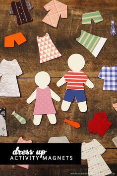 paper dolls and clothes laid out on a wooden surface with one doll standing next to the other