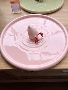 there is a pink plate with a red object in it on the table next to other plates