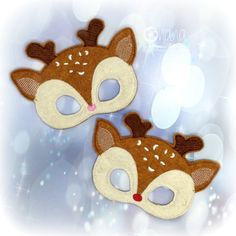 two brown and white deer masks on a blue background with snowflakes in the background