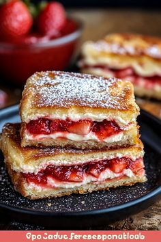 strawberry shortcakes stacked on top of each other with powdered sugar and strawberries in the background