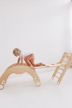 a young child is playing on a wooden bed frame with ladders attached to it