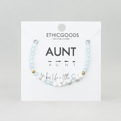 the white and gold beaded bracelet is on display in front of a card that says,