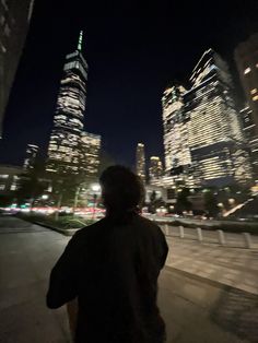 a man standing in front of tall buildings at night