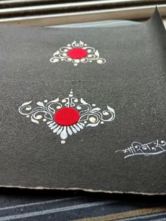 a close up of a piece of paper with red and white designs on the side