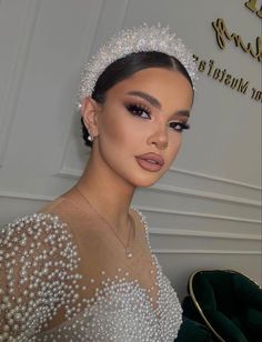 a woman with pearls on her head wearing a tiara and posing for the camera