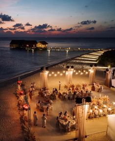 an aerial view of a wedding on the beach at night with lit up tables and chairs