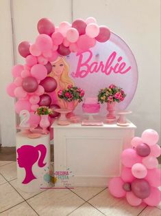 a table with balloons, vases and flowers on it in front of a sign that says barbie