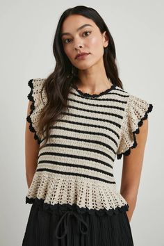 a woman wearing a black and white striped top with ruffles on the shoulders