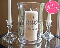 two candles are sitting on a table next to a glass vase with the word sale written on it