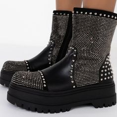 The Azalea Wang Blinged Up Mode Flatform Bootie In Black Is A Glimmering Chelsea Bootie Featuring A Vegan Leather Upper, Rhinestone Gemstone Detailing, Pyramid Studded Accents, And A Tonal Platform Base. Complete With A Chunky Heel, Rounded Toe, Inner Ankle Zipper, And A Mid Calf Height Shaft. - All Man-Made Materials - 7” Shaft Height - 2.5” Heel Height Glamorous Leather Boots With Silver Studs, Leather Bling Boots With Round Toe, Leather Boots With Bling And Round Toe, Silver Studded Boots For Night Out, Bling Leather Boots With Round Toe, Silver Spiked Round Toe Boots, Evening Boots With Silver Studs And Round Toe, Silver-studded Boots With Round Toe For Evening, Silver Platform Boots For Night Out