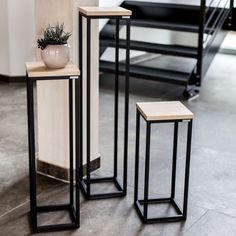 three black metal and wood tables with a plant in the middle one on each side