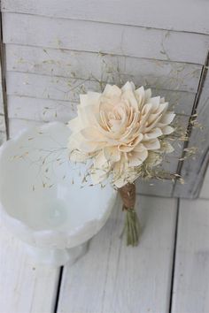 a bouquet of flowers sitting on top of a white bowl next to a wooden wall