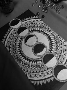 an artistic drawing on paper with circles and shapes in black and white, sitting on a table