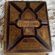 an old book with writing on it sitting on a lace tablecloth covered table cloth