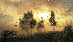 the sun is shining through raindrops on a window with buildings in the background