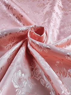 the fabric is pink and has white flowers on it, as well as an intricate design