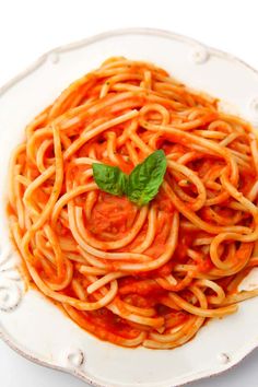 spaghetti with tomato sauce and basil on white plate