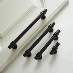 four black handles on a white door and some knobs in front of the mirror