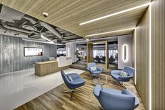 an office lobby with blue chairs and wooden floors