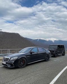 two mercedes benzs are parked on the road in front of some mountains and snow