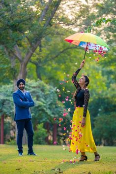 a woman holding an umbrella in the air while standing next to a man on a field