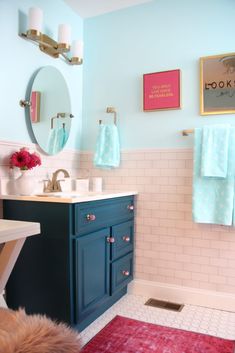 a bathroom with blue cabinets and pink rug