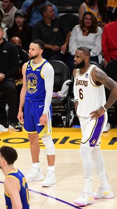 two basketball players standing next to each other in front of an arena full of people