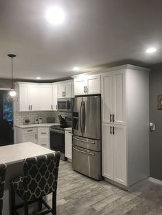 a kitchen with stainless steel appliances and white cabinetry, along with gray walls in the background