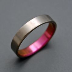 a pink and gold wedding ring sitting on top of a gray surface with a black diamond in the center