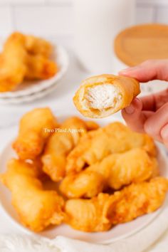 a person holding a piece of food up to the camera while it is on a plate