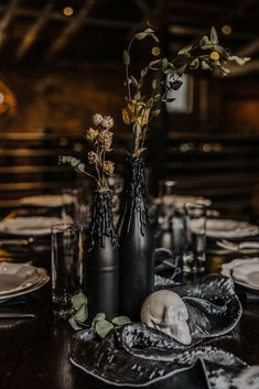 the table is set with black vases and plates