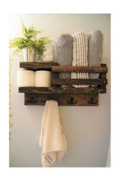 a wooden shelf with towels and other bathroom items on it, hanging from the wall