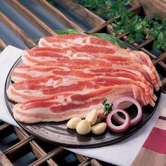 a plate with raw meat and onions on it sitting on a table next to some vegetables