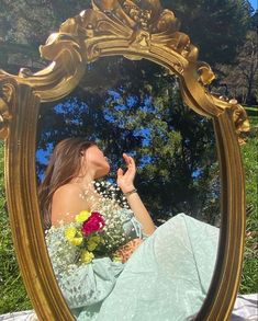 a woman sitting on the ground in front of a mirror holding a bouquet of flowers