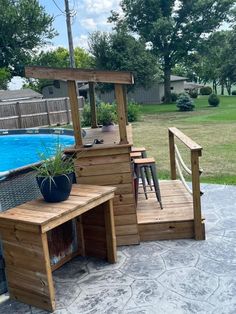 a wooden bench sitting on top of a patio next to a swimming pool with a potted plant