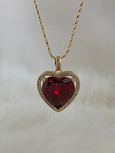 The Ruby Heart Necklace is enchanting! This heart necklace came straight out from a rom-com! It features a large heart-shaped cubic zirconia ruby crystal hugged in a micro pave frame and suspended on a dainty twisted box chain necklace. She takes all other ruby heart necklaces off the scene! Available in 24K gold or rhodium plating over steel Patent plating & sealant technology to ensure durability and long lasting wear Made in Los Angeles, CA | Nickel & Lead Free Ruby Necklace Aesthetic, Ruby Heart Charm Necklace, Red Heart-cut Cubic Zirconia Necklace, Red Heart Cut Cubic Zirconia Necklace, Red Cubic Zirconia Heart Pendant Necklace, Red Heart-shaped Cubic Zirconia Necklace, Gold And Red Necklace, Red And Gold Necklace, Ruby Gold Necklace